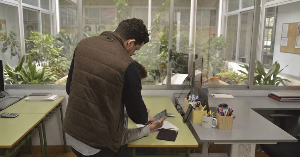Profesor ayudando a un estudiante a resolver ejercicios en una academia mientras prepara la PAU.