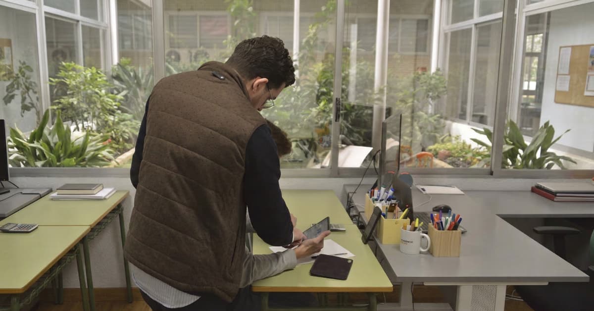 Profesor ayudando a un estudiante a resolver ejercicios en una academia mientras prepara la PAU.